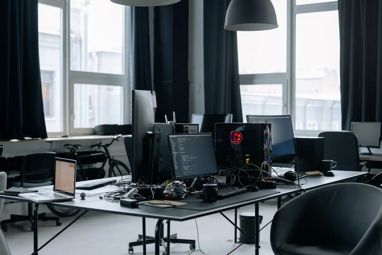 Workstation desk with many computers and laptop and messy desk