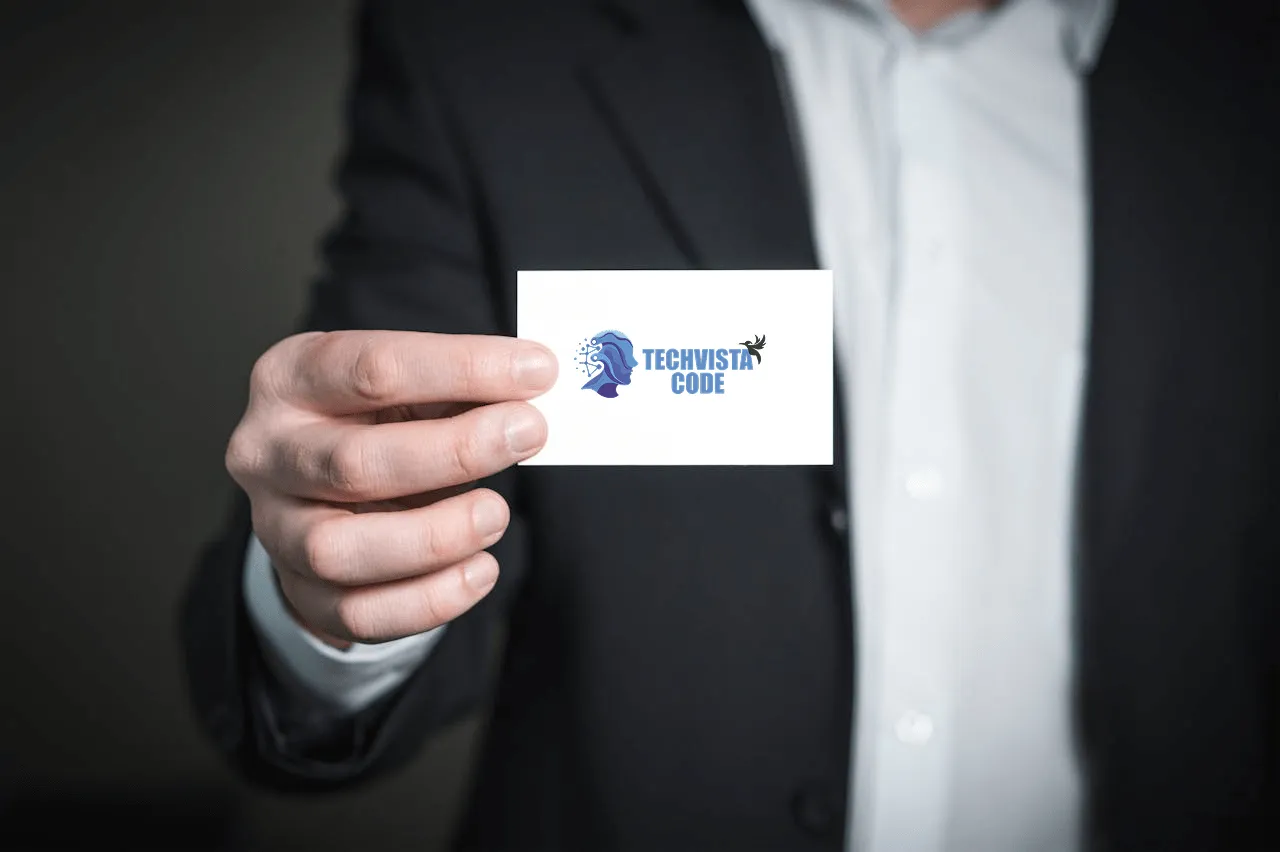 A person in black suit holding tech vista code business card