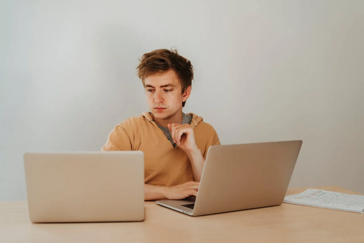 A guy working on two laptops