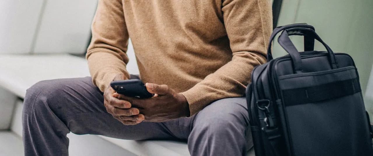a man holding a phone with a laptop bag