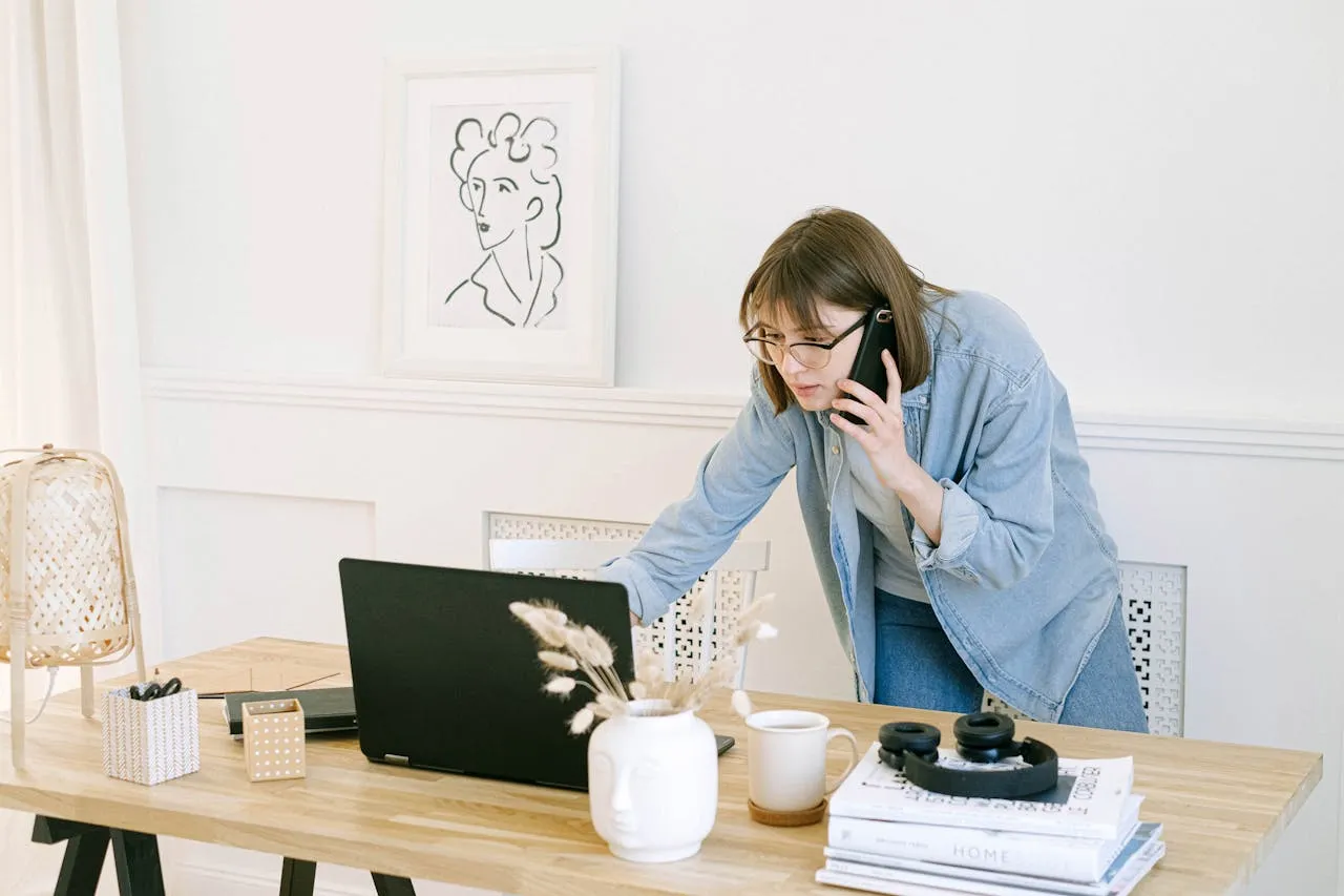 A girl looking at her laptop and talking over phone