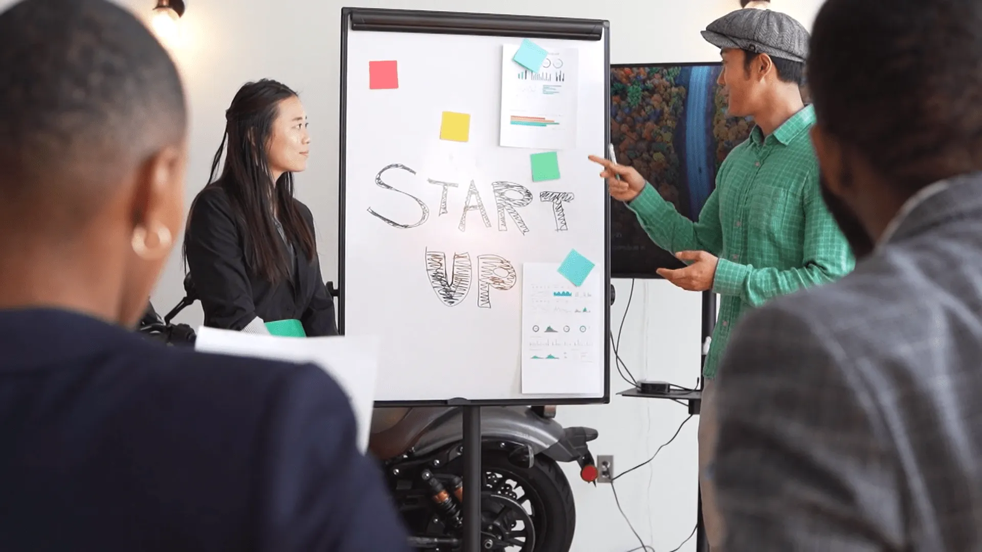 A girl and a guy pitching their idea with a whiteboard behind them
